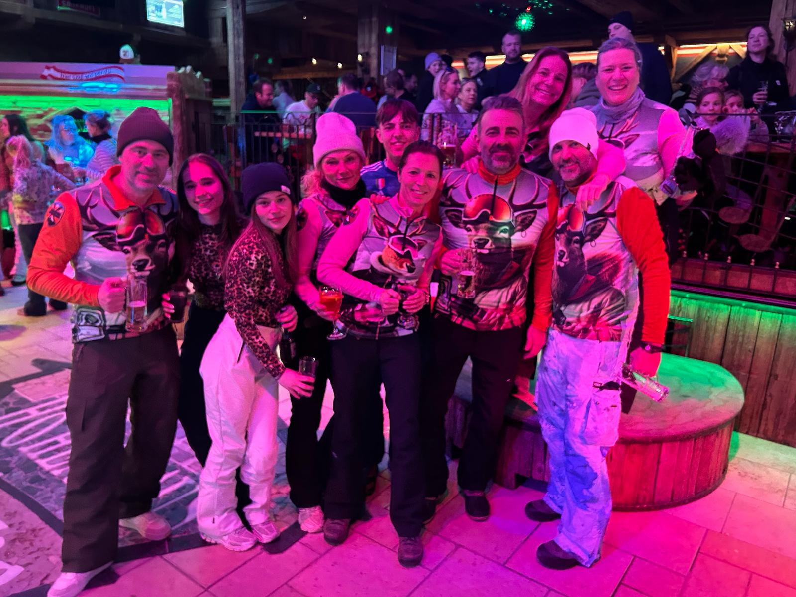 Groepsfoto van mensen in een Apres Ski bar die skipullies aan hebben van het merk Gutski